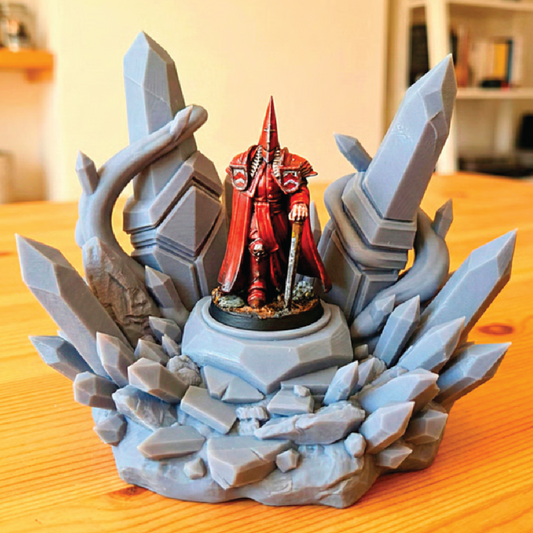 Figurine in red attire on a rocky base with crystals, set against a blurred indoor background.