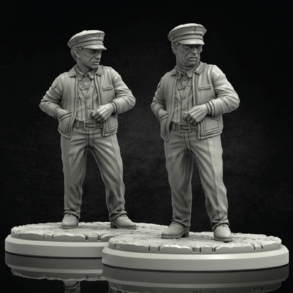 Two unpainted gray miniature figurines of elderly men in military-style uniforms standing on round bases against a dark studio background.