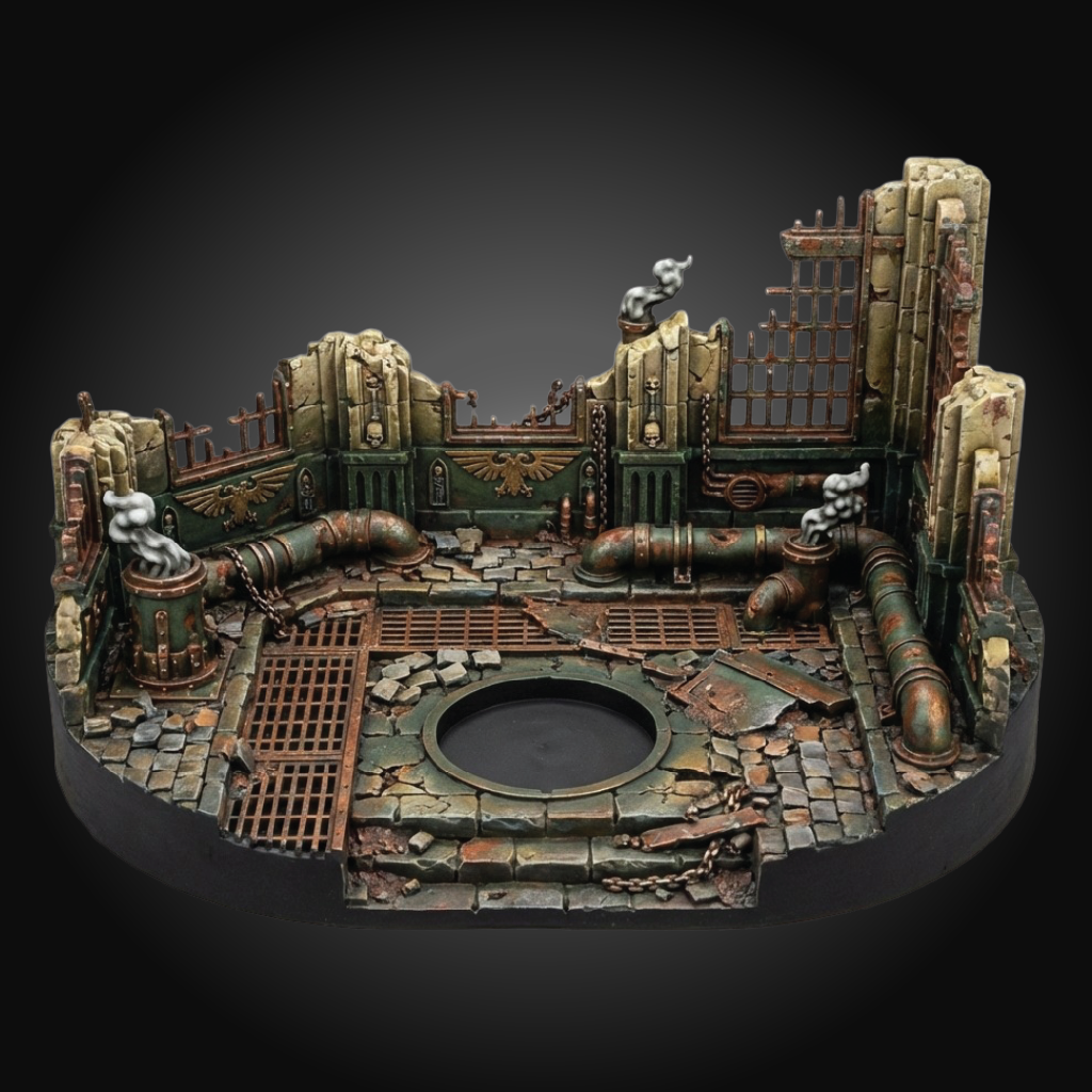 A miniature tabletop terrain piece depicting a ruined industrial or sci-fi factory interior with pipes, grates, broken walls, and a circular opening, shown on a black background.