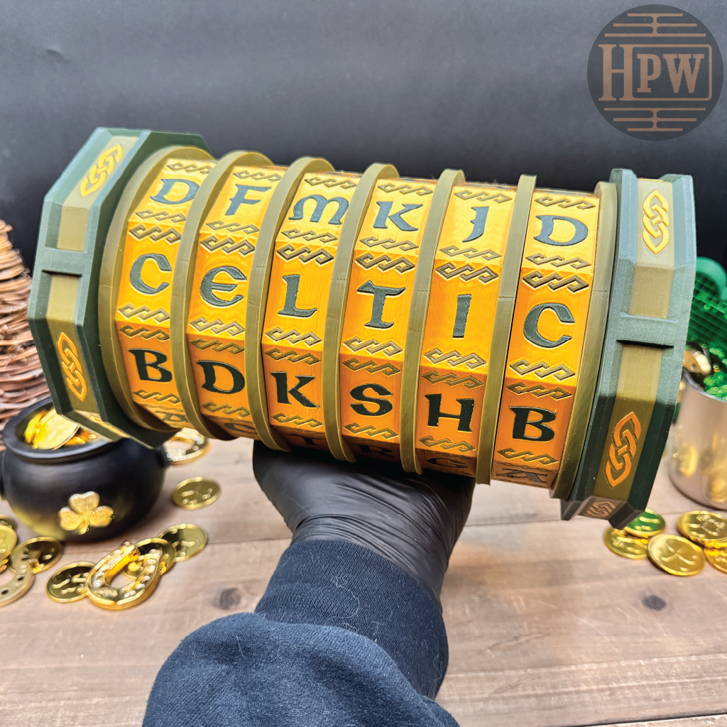 Decorative box with Celtic lettering held by a gloved hand on a wooden surface with gold coins and a pot of gold.