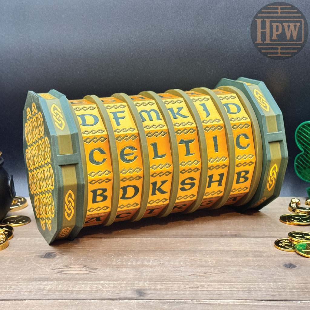 Decorative cylindrical object with Celtic lettering on a wooden surface, featuring the brand 'HPW'.