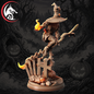 A detailed 3D-rendered miniature figurine of a skeletal witch riding a broomstick over a graveyard base, with glowing orange flames at the end of the broom and a circular wolf logo in the top-left corner.