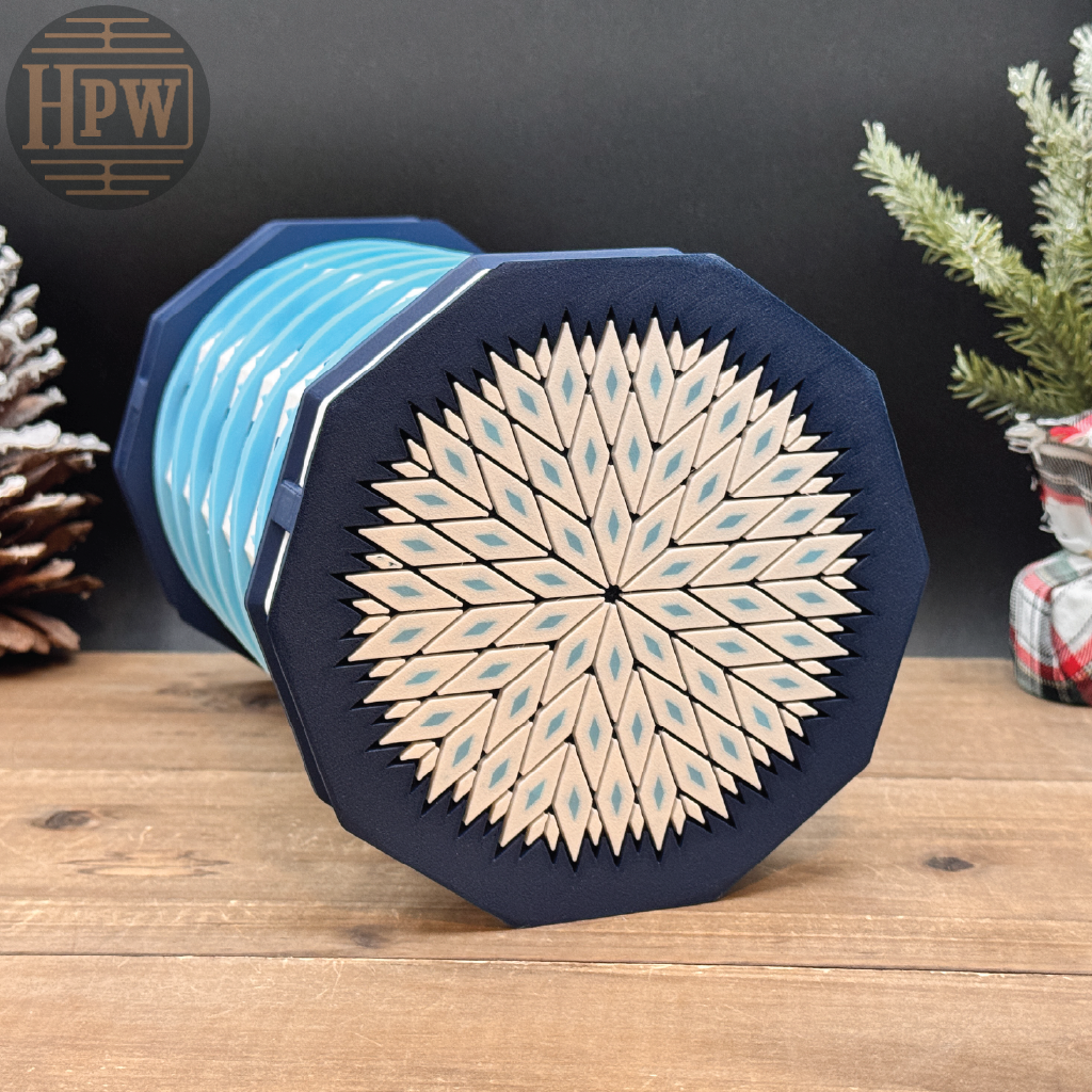 Decorative box with geometric design on a wooden surface, featuring the brand 'HPW'.