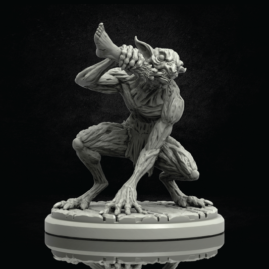 A gray unpainted fantasy creature figurine in a crouching pose, holding a severed head in its hands, displayed on a circular base against a dark background.