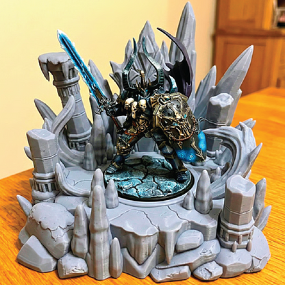 Fantasy figurine with a warrior in armor and a sword, surrounded by rocky landscape on a wooden surface.
