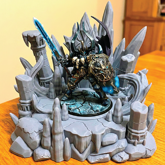 Fantasy figurine with a warrior in armor and a sword, surrounded by rocky landscape on a wooden surface.