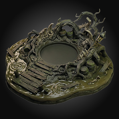 A highly detailed miniature tabletop terrain piece depicting a swampy, gnarled tree-root landscape with a central circular pool, wooden planks, barrels, and a lantern, shown on a dark gradient background.