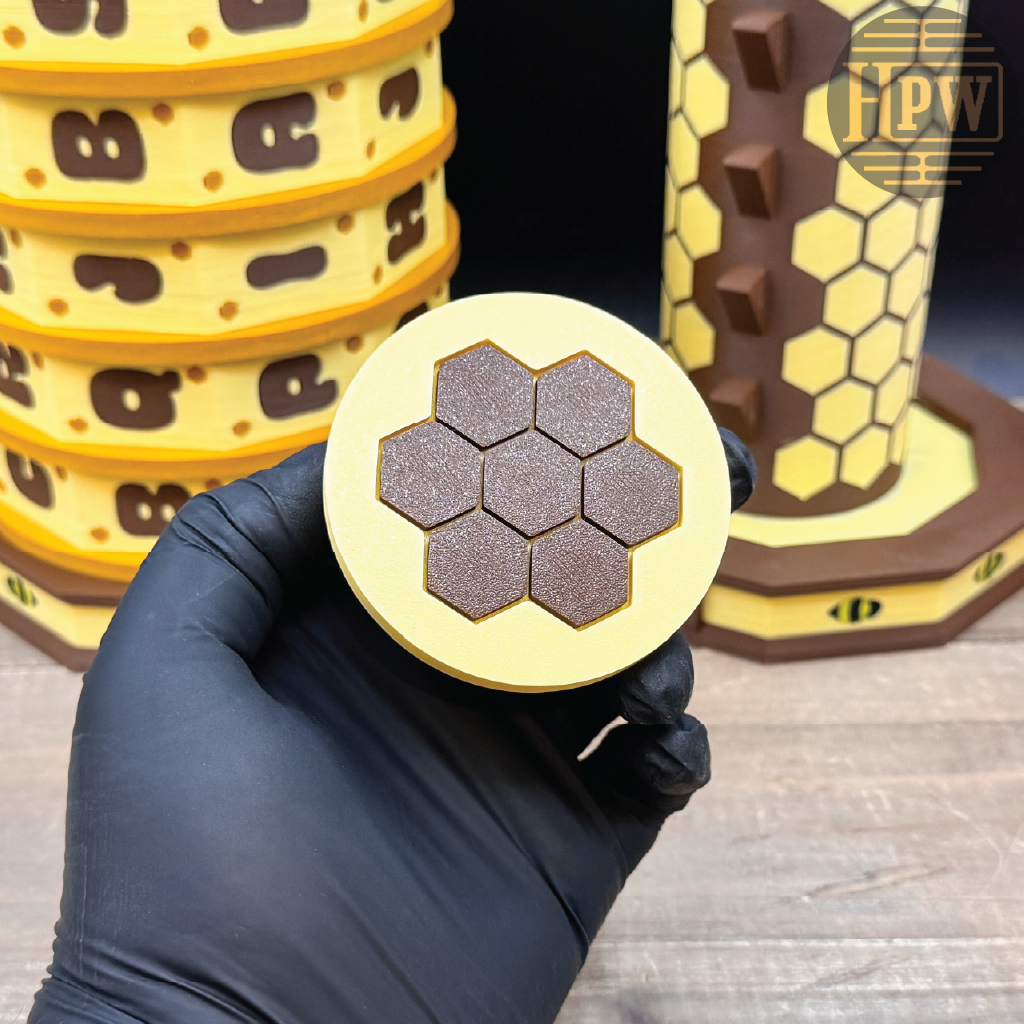 Hand holding a circular object with honeycomb pattern, surrounded by similar objects on a wooden surface.