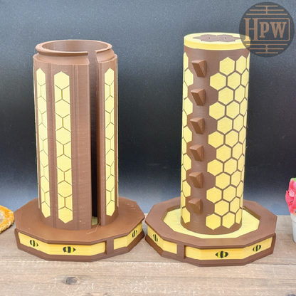 Two cylindrical honeycomb-shaped objects on a wooden surface with a dark blue background.