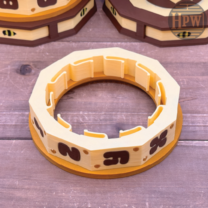 Wooden bee hive frame on a wooden surface with 'HPW' branding.