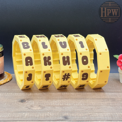 Yellow bracelet with letters and symbols on a wooden surface with a dark background