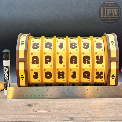 Yellow and brown puzzle wheel with letters, next to a ruler for scale, on a wooden surface.
