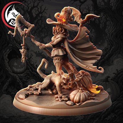 A fantasy tabletop miniature figurine of a horned female warrior with bat wings, holding a staff topped with a skull, standing over a cat-like creature and a pumpkin on a circular base. The figure is shown against a dark illustrated background with trees and pumpkins.