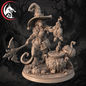 An unpainted fantasy tabletop miniature of a cat-like witch character standing on a round base, holding a severed bird and a large mace, with a cauldron, pumpkins, and magical props around it. The figure is shown against a dark spooky forest background, with a red-and-black dragon logo in the top-left corner.
