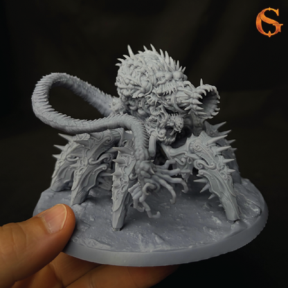 A hand holding a gray unpainted fantasy monster miniature figurine against a dark background. The creature has a spiky, multi-limbed body, a long curled tail, and sharp claws, shown in a monochrome light gray resin/plastic finish.