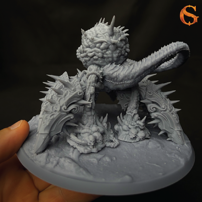 A detailed, unpainted grey fantasy miniature of a spiky, reptilian creature on a round base, held by a hand against a dark background.