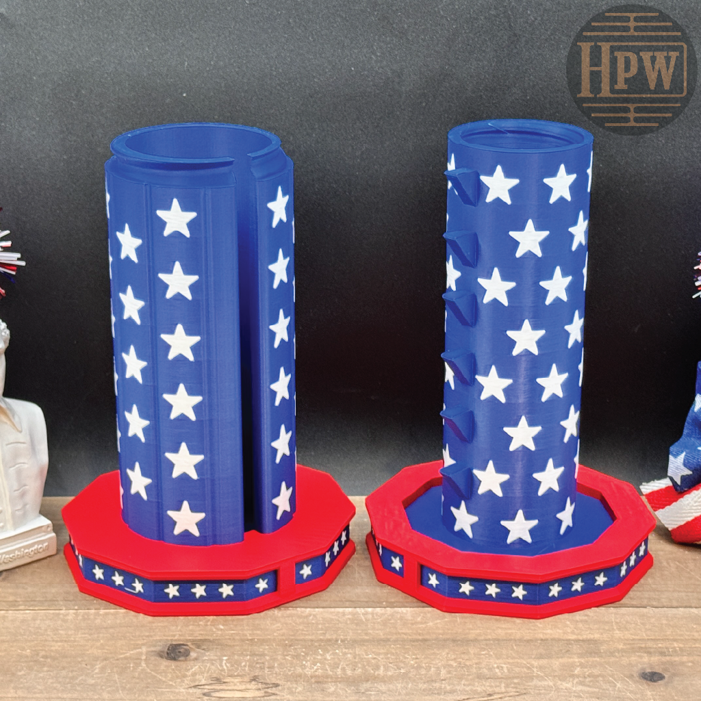 Two patriotic-themed cylindrical holders with blue bodies covered in white stars and red octagonal bases, displayed on a wooden surface against a dark backdrop.