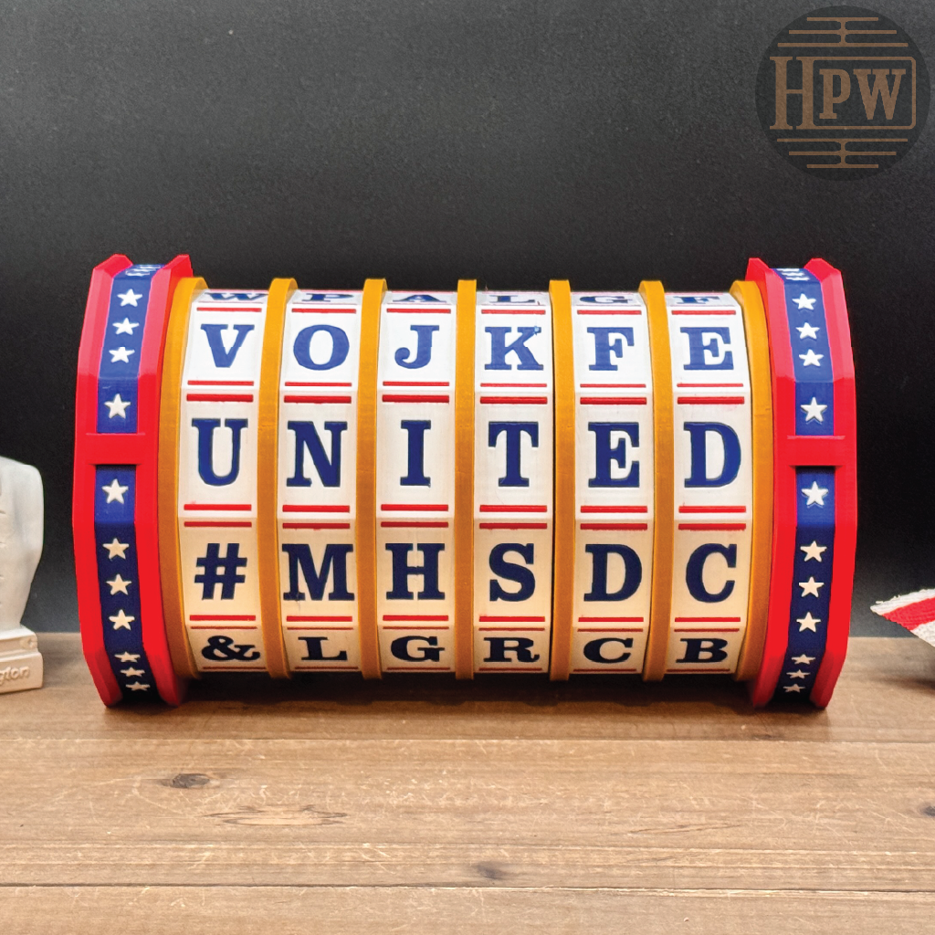 A novelty rolling letter lock sign featuring red, white, and blue segments that spell out 'VOJ KFE UNITED #MHSDC &L GRCB' with a red, white, and blue striped end cap. The sign is displayed on a wooden surface against a dark background.