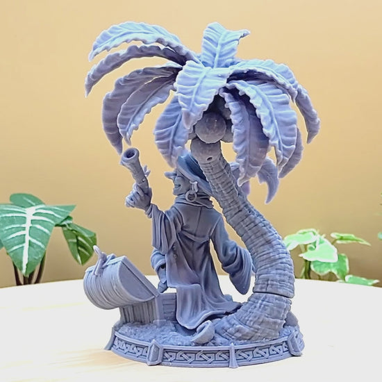 A goblin pirate wielding miniature blunderbusses standing under a palm tree and on top of an open treasure chest full of coins. This is a model 3D printed in gray UV resin.