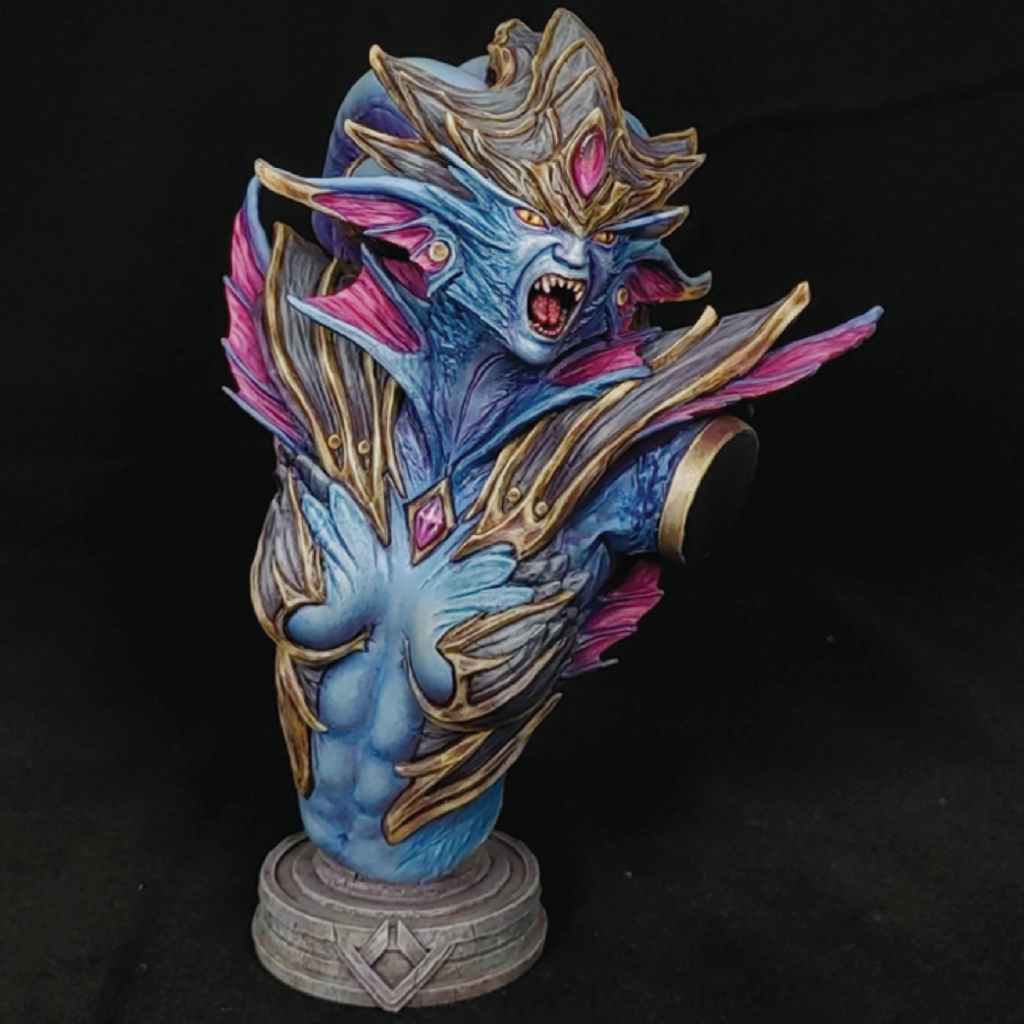 Detailed fantasy sculpture of a dragon-like creature with blue, gold, and pink colors on a black background.