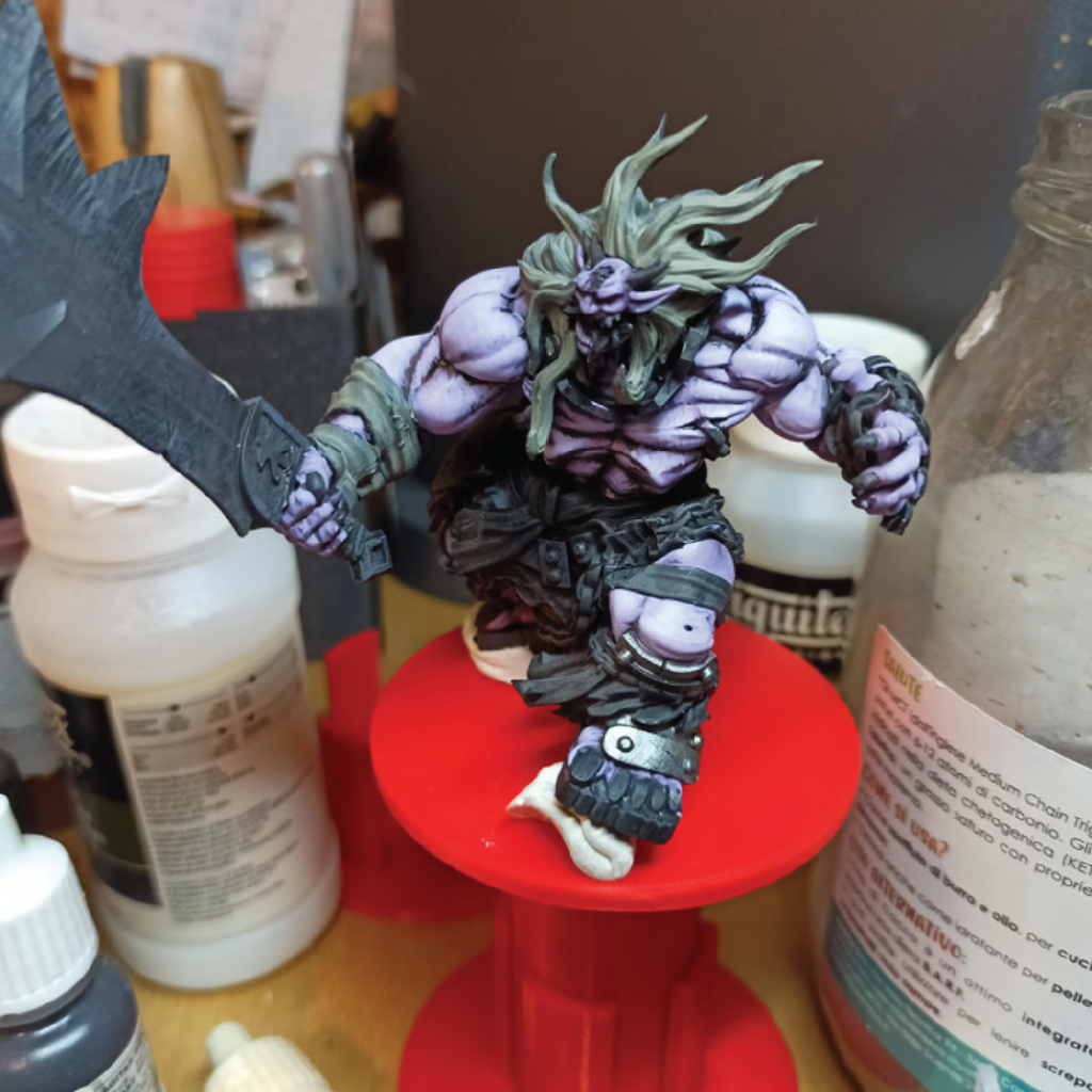 Action figure on a red stand with paint bottles in the background