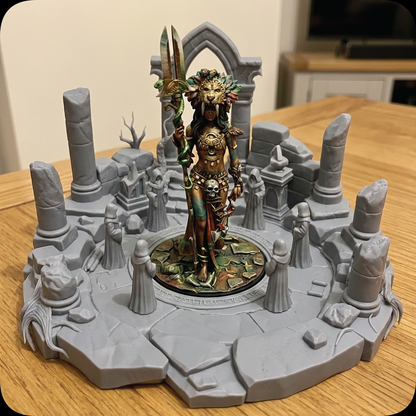 A painted tabletop miniature figurine of a female warrior standing in a ruined stone arena, displayed on a wooden table with a blurred indoor room in the background.