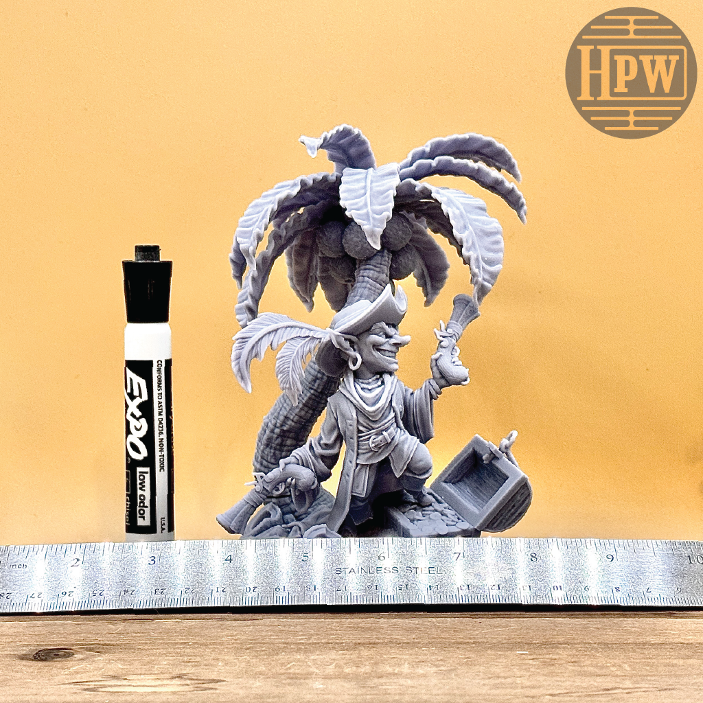 A goblin pirate wielding miniature blunderbusses standing under a palm tree and on top of an open treasure chest full of coins. This is a model 3D printed in gray UV resin.
