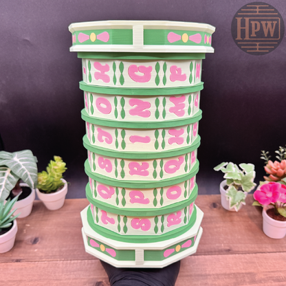 Stack of decorative planters with pink and green design on a wooden surface.