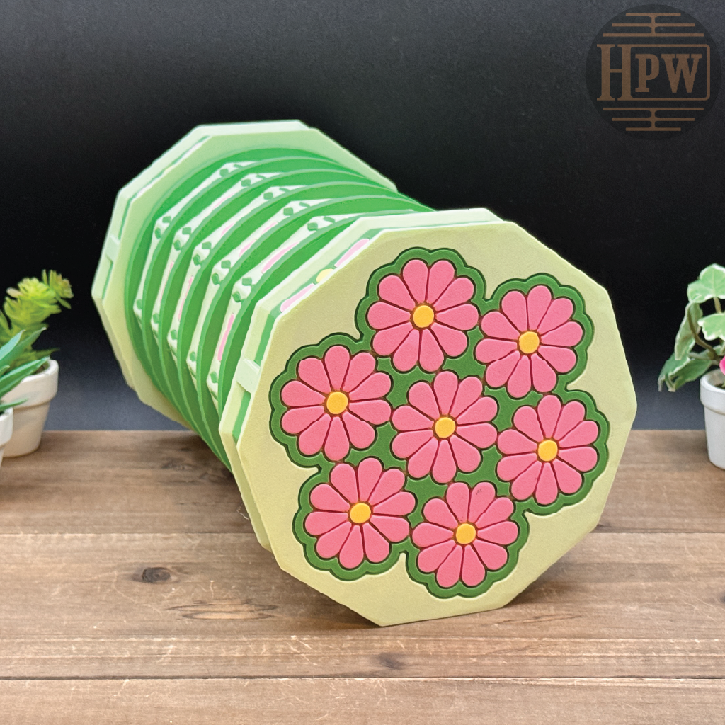 Stack of hexagonal coasters with floral design on a wooden surface, brand 'HPW' visible.