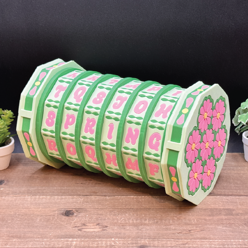 Decorative cylindrical object with floral patterns and text on a wooden surface.
