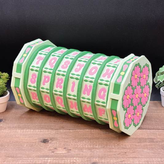 Decorative cylindrical object with floral patterns and text on a wooden surface.