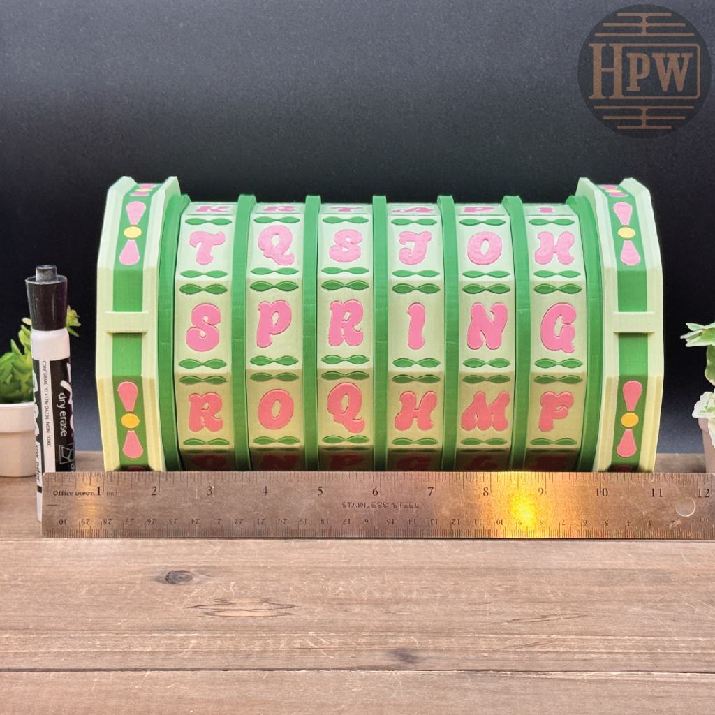 Green and pink letter block with a ruler for scale on a wooden surface