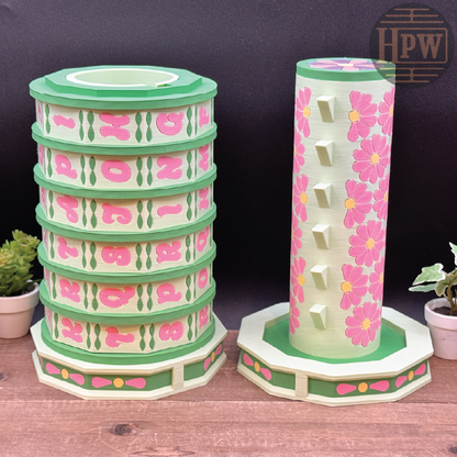 Stackable decorative towers with floral design on a wooden surface, featuring the brand 'HPW'.