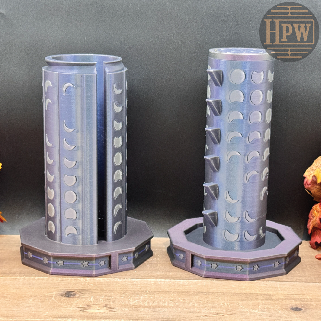 Two 3D-printed cylindrical moon-phase candle holders with octagonal bases, displayed on a wooden surface against a dark gray background.