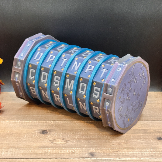 A 3D-printed cosmic-themed wheel or spinner toy with blue bands, silver lettering, and a purple face, resting on a wooden surface against a dark background.