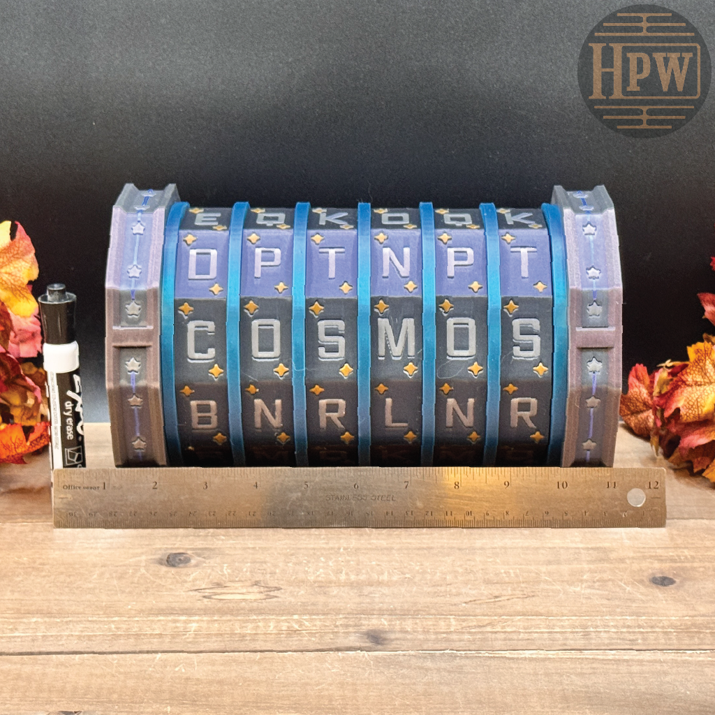 A 6-flip LED clock displaying the word 'COSMOS' in gold letters on blue and gray segments, shown on a wooden surface with a metal ruler in front for scale. The background is dark gray with autumn leaves on the sides and an 'HPW' logo in the top right corner.