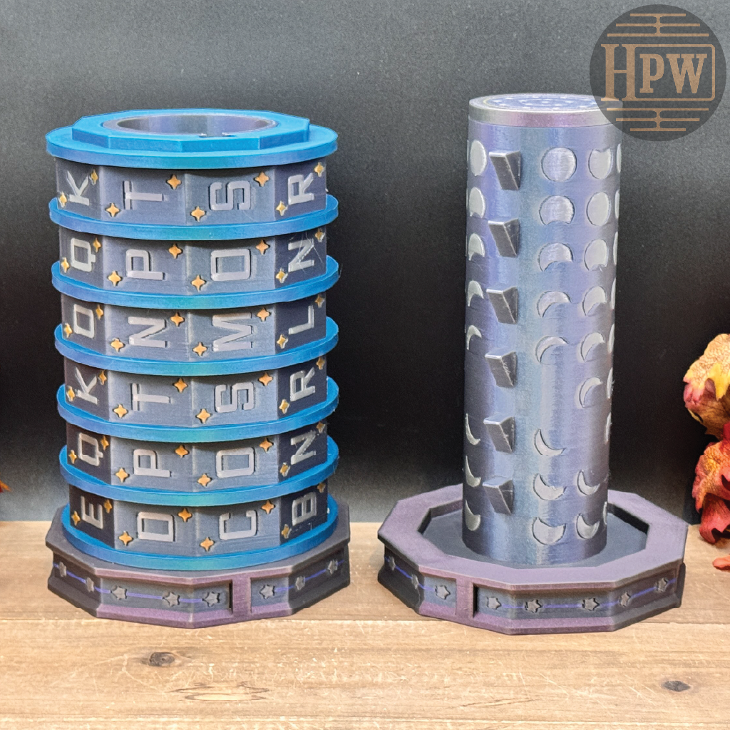A 3D-printed cylindrical puzzle box set with a blue and gray stacked cylindrical container on the left and a separate matching gray cylindrical container on the right, displayed on a wooden surface against a dark gray background.