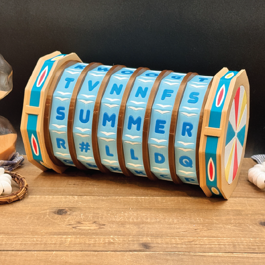 A wooden summer-themed calendar wheel toy with blue lettered faces, brown bands, and colorful side accents, displayed on a wooden tabletop against a dark backdrop.