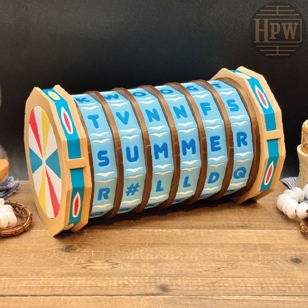 A decorative wooden letter spinner cylinder with blue letter tiles spelling out words like SUMMER, displayed on a rustic wooden surface against a dark background.